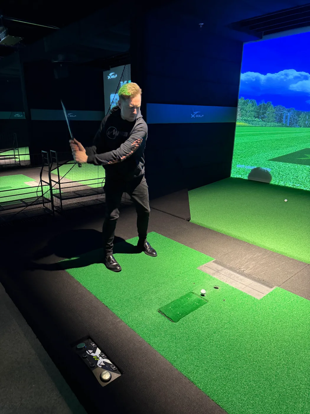 A member of the Barley and Mane team taking a swing at the indoor golf simulator