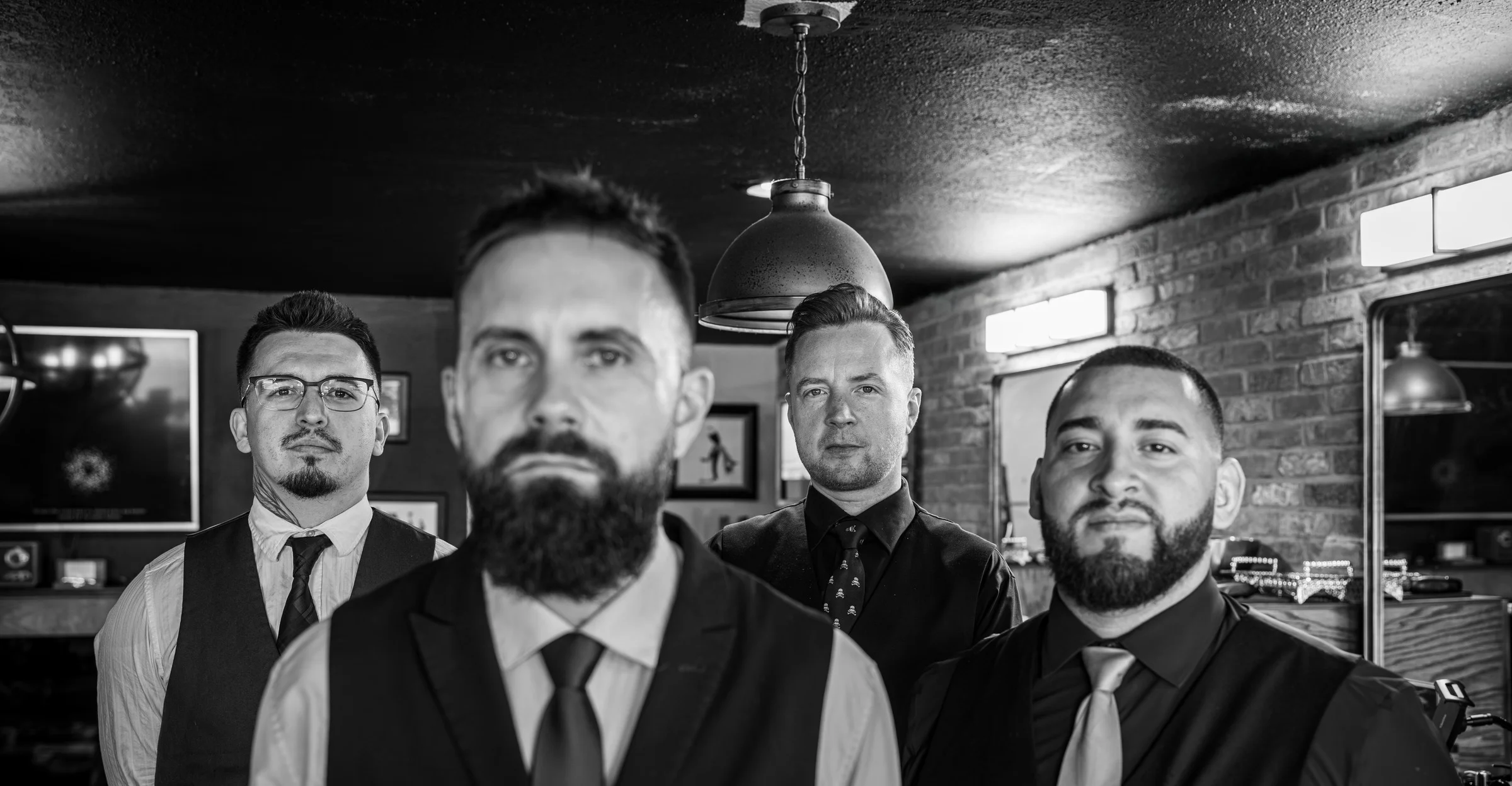 A black and white portrait of the Barley and Mane barbers in vests and ties inside the shop