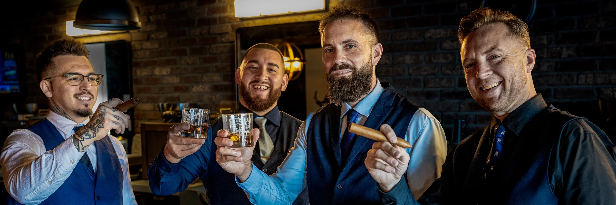 Two Barley and Mane barbers laughing and raising glasses of whiskey, one holding a cigar