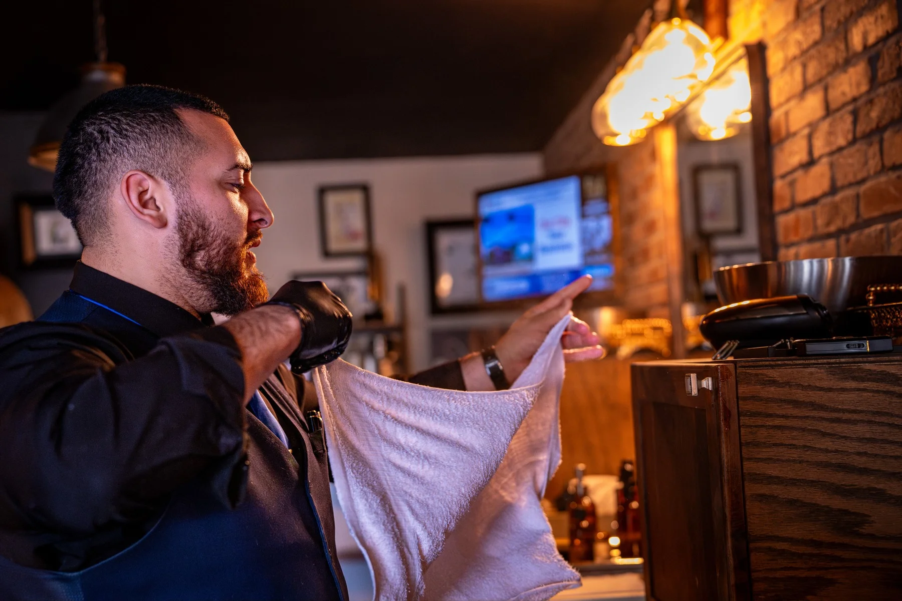 A Barley and Mane barber shaking out a towel beside his station in the shop