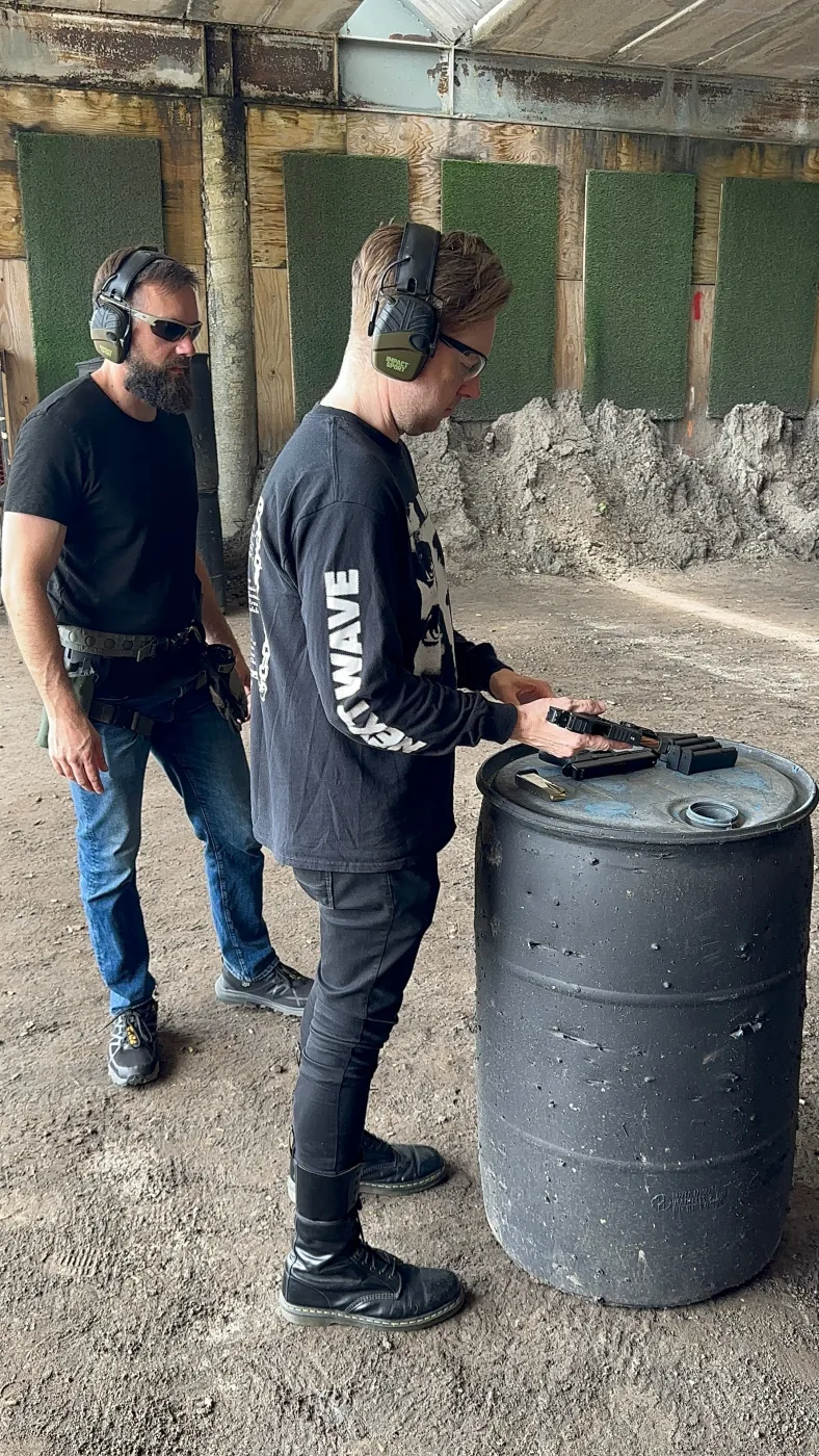 Two members of the Barley and Mane team in ear and eye protection at an outdoor shooting range, one loading at the bench