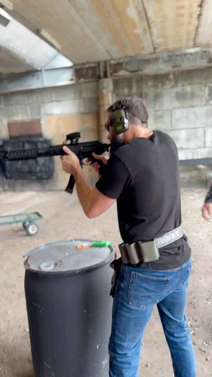 A member of the Barley and Mane team shouldering a rifle at an outdoor shooting range