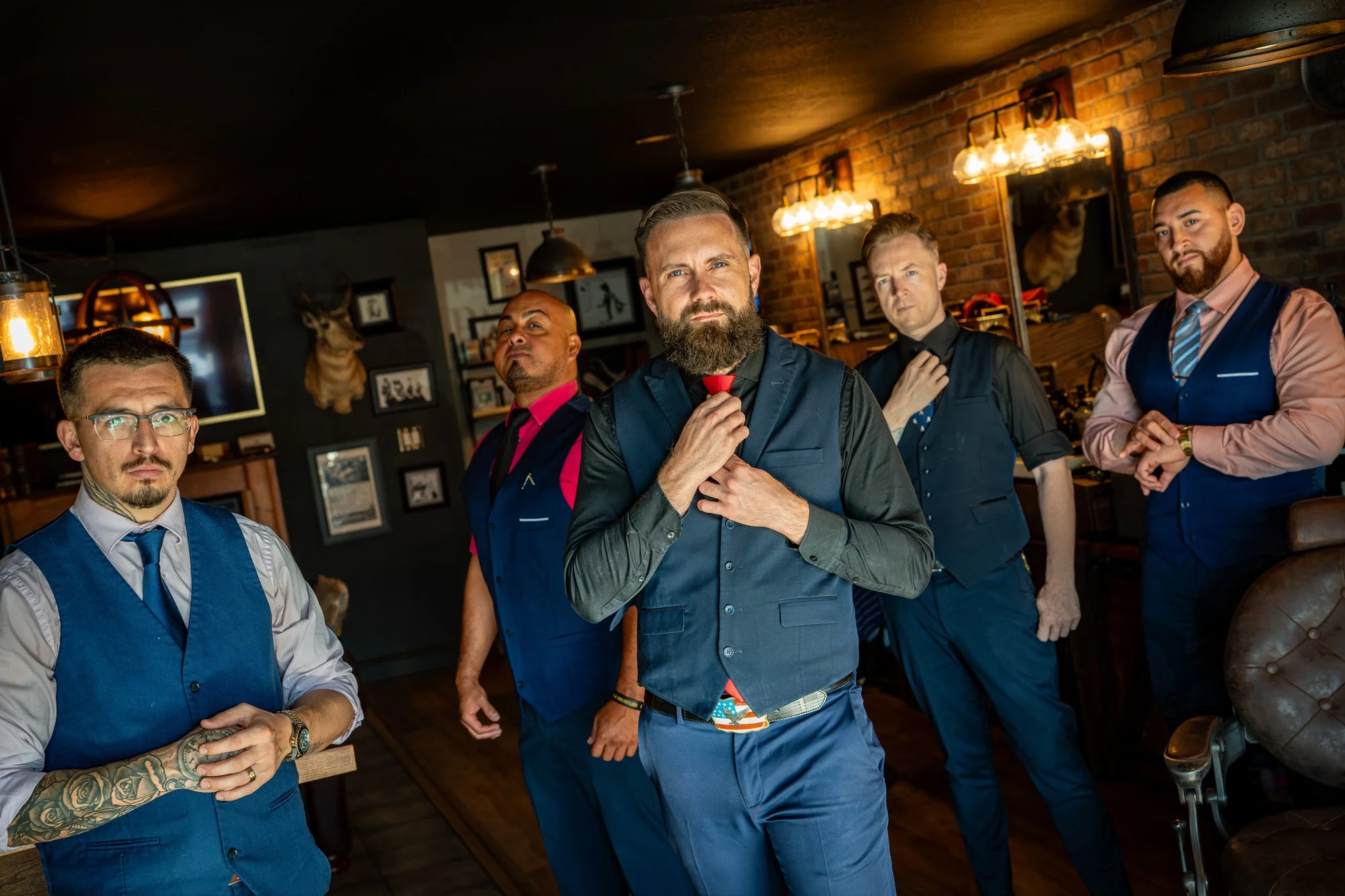 Five Barley and Mane barbers in vests straightening their ties inside the shop