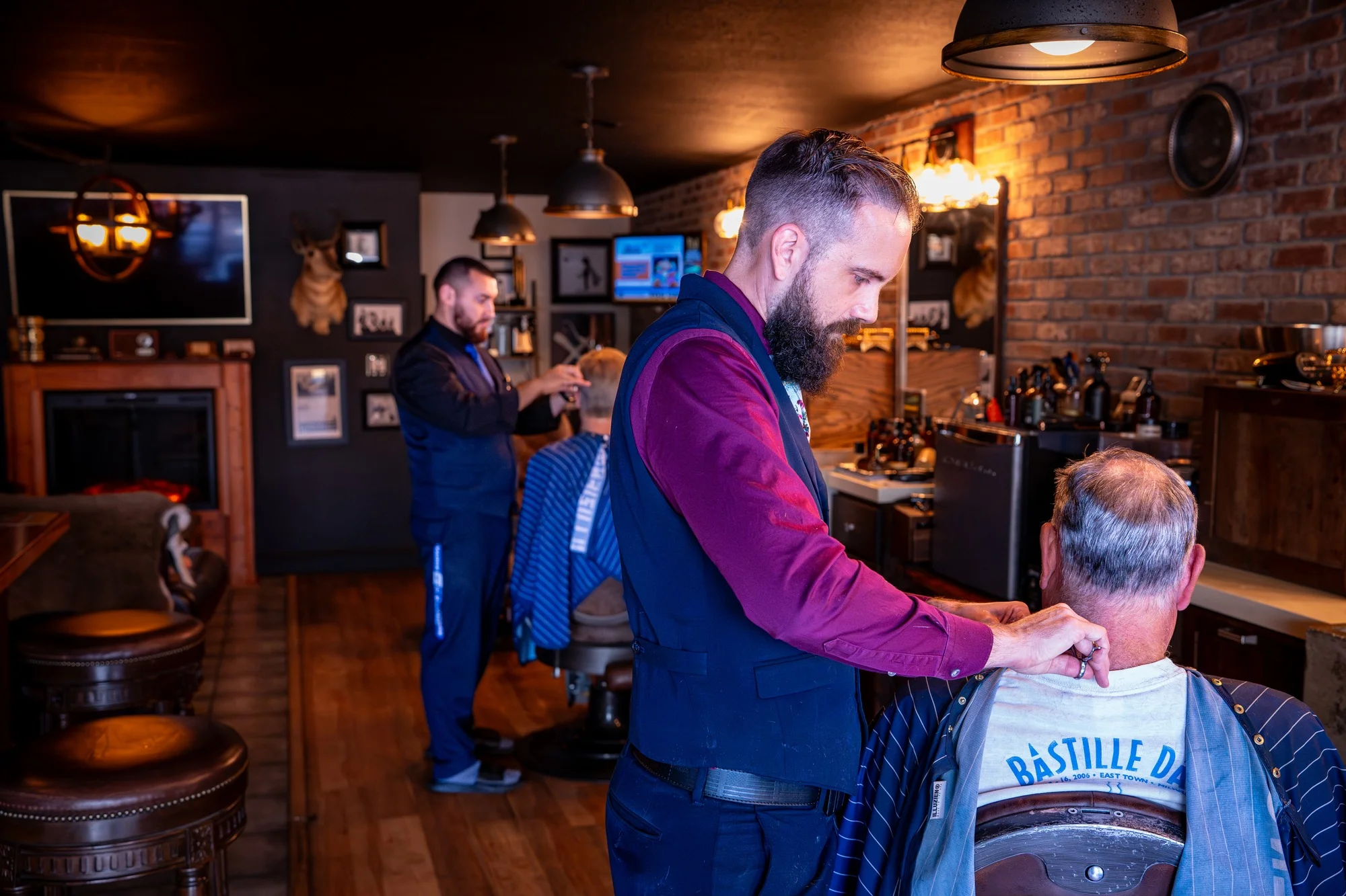 Owner Ryan cutting a client's hair on the Barley and Mane shop floor, another barber working behind him