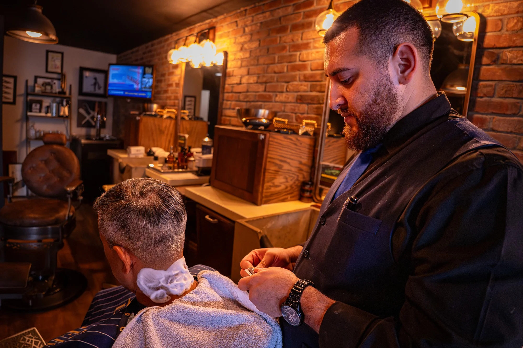 A Barley and Mane barber finishing a client's cut, a towel around the client's shoulders