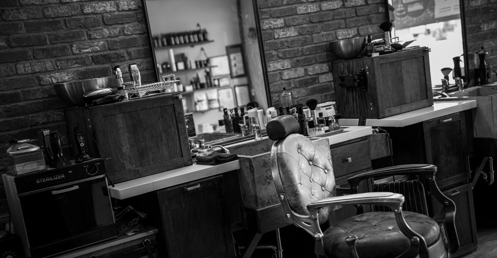 An empty vintage barber chair at its station in the shop, in black and white